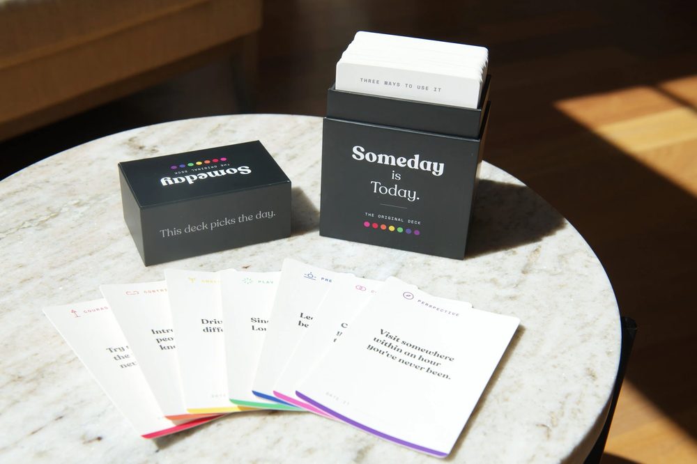 The Someday Is Today card deck box with prompt cards fanned out on a marble table