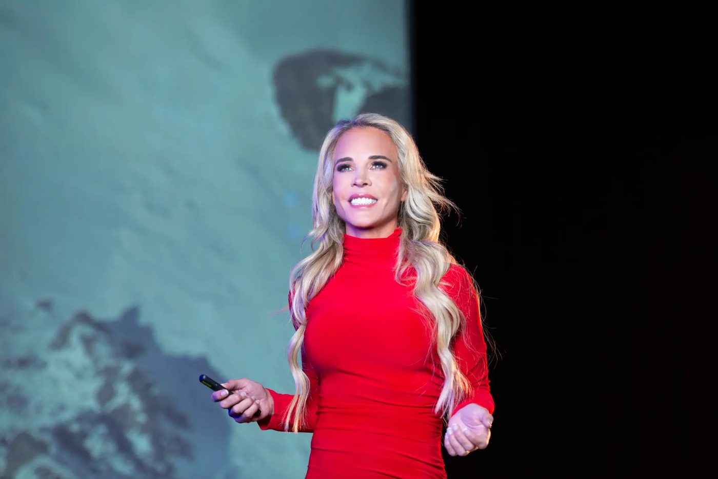 Jenn Drummond speaking on stage in a red dress